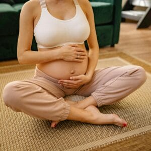 Expectant mother sitting in a serene setting practicing meditation and mindfulness indoors.